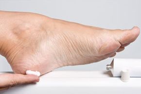 A woman's hands applying moisturizing cream to dry feet