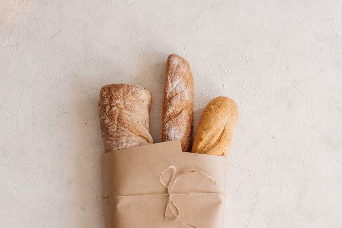 Three loaves of bread wrapped in brown paper