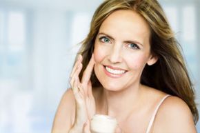 A woman gently applies facial cream.