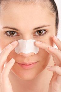 A young woman applying a pore-clearing strip to her face (beauty and skincare concept)