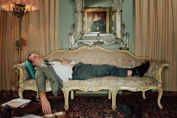 A man in a suit napping on an elegant sofa.
