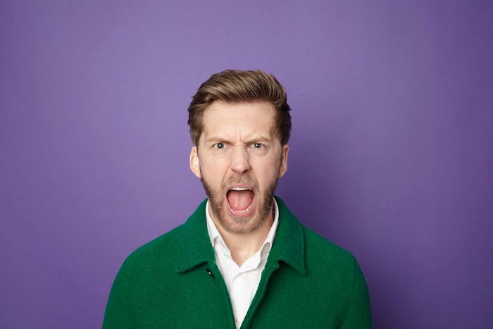 A man in a green sweater yelling against a purple background.