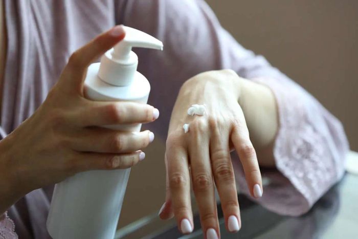 A woman applying lotion to her hands.