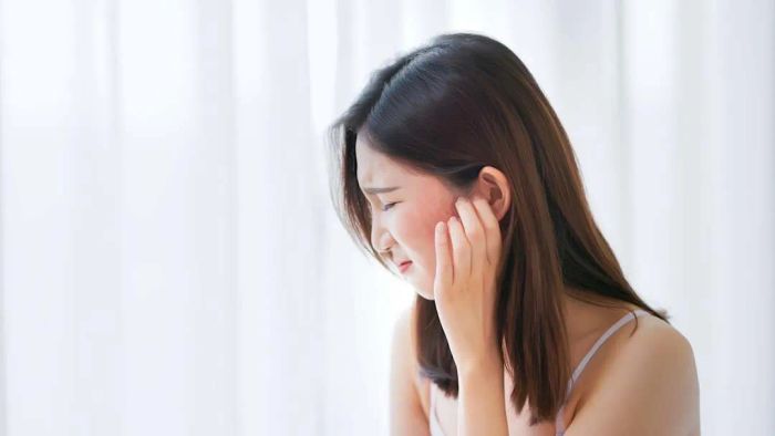 A woman scratching the side of her face.