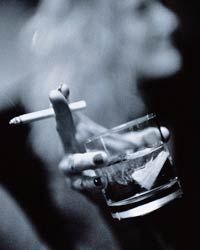 A hand holding a drink and a cigarette