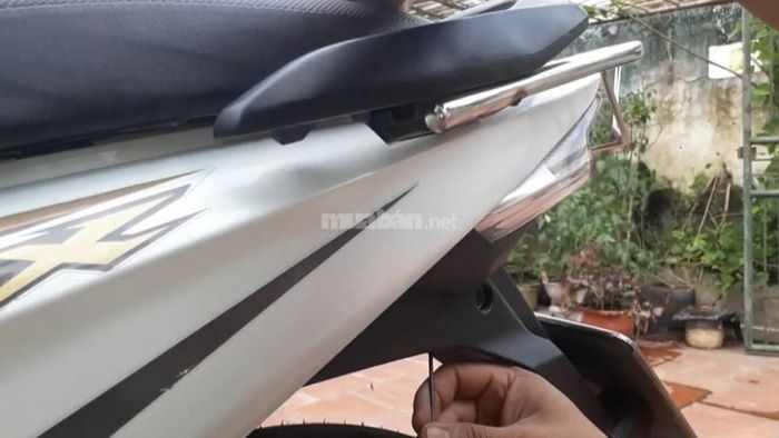 Dùng móc cắm vào lỗ, đẩy sâu và xoay ngược chiều kim đồng hồ để mở cốp xe