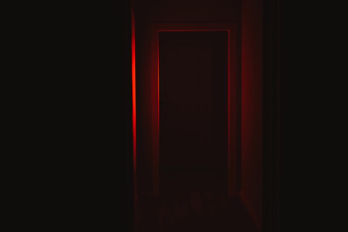 Stock image of a door illuminated by red light in a haunted house.