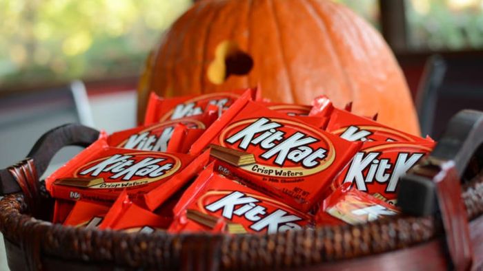 Kit Kat bars arranged in a basket next to a jack-o'-lantern.