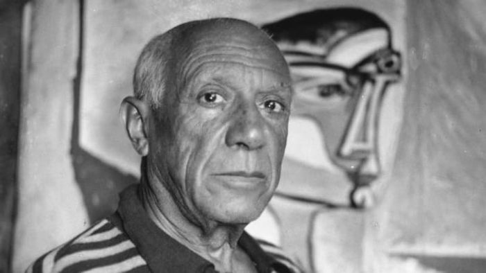 Pablo Picasso posing in front of one of his masterpieces.