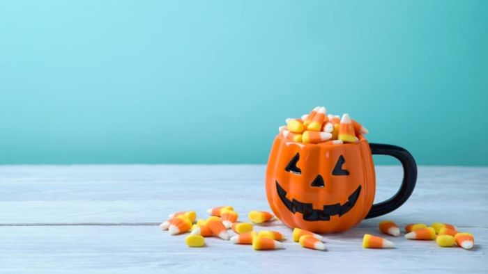A jack-o-lantern mug filled with candy corn.