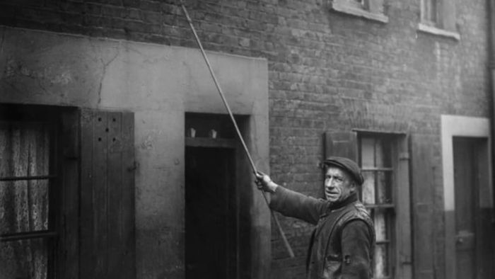 A knocker-up at work in London in 1929.