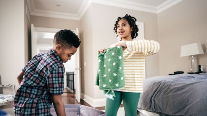 Two children folding laundry together.