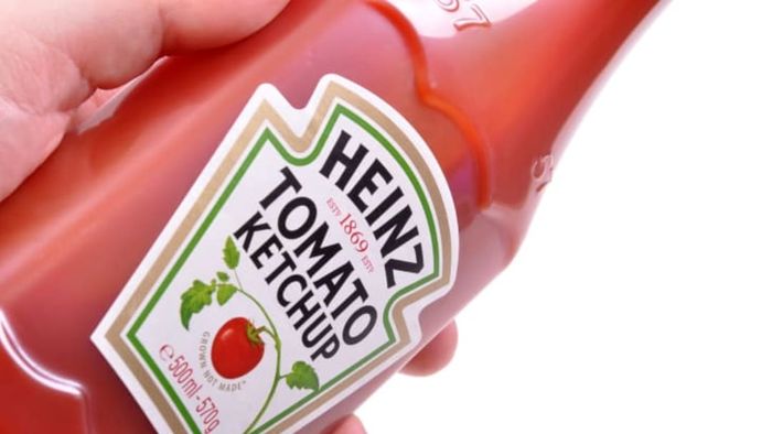 A hand holding a ketchup bottle.