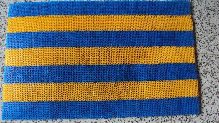 A vibrant blue and yellow doormat crafted from straws.