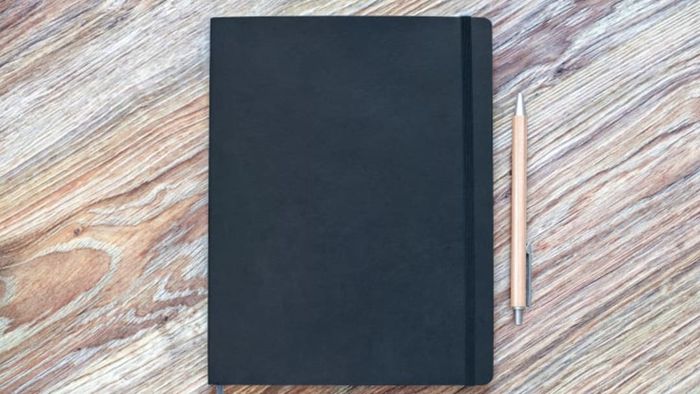 A planner resting on a wooden table with a pen beside it.
