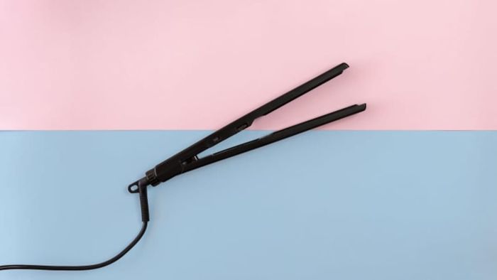 A flat iron placed on a pastel-colored background.