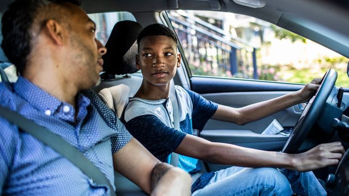 A father guiding his son through driving lessons.