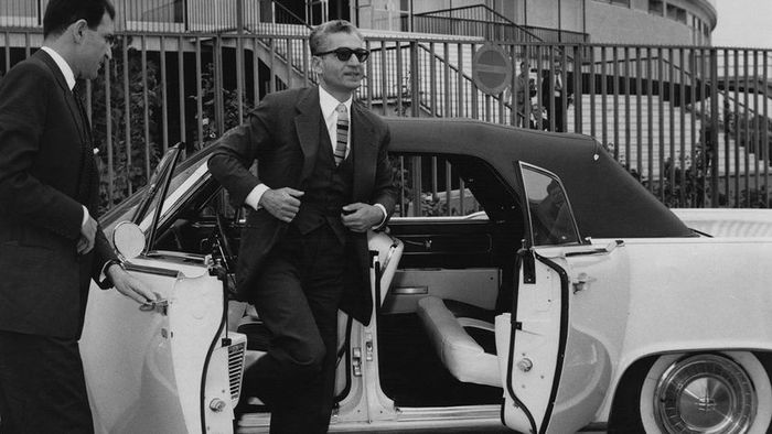 The Shah of Iran exiting a Lincoln Continental featuring suicide doors.