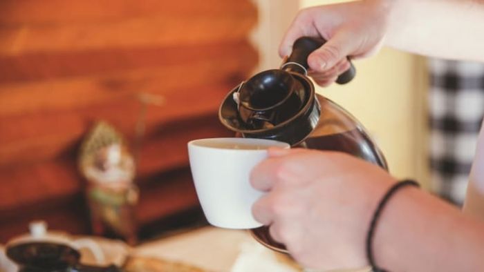 hands pouring a cup of coffee