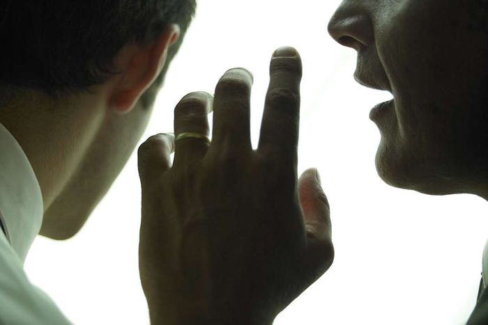 Businessman whispering in another businessman's ear