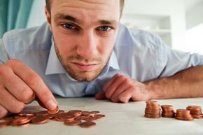 A frustrated young man in a collared shirt stares at a pile of pennies.