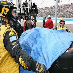 During a rain delay, crew members cover up the tires to protect them from the elements.