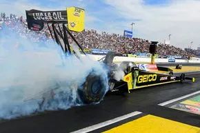 Driver Richie Crampton showcases the GEICO Top Fuel dragster in a dramatic, smoke-filled burnout.