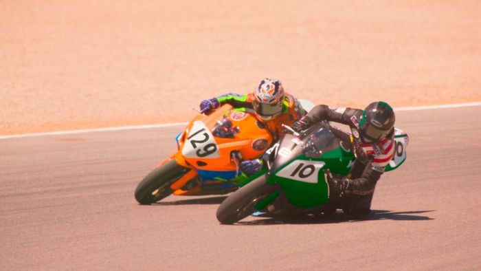 Two racers on motorcycles, speeding across sandy terrain.