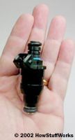 A fuel injector resting in the palm of a hand.