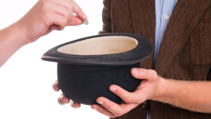 A person placing money into another person's hat.