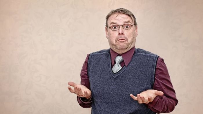 A man wearing a vest and tie, shrugging.