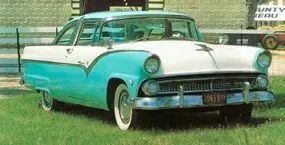 A teal 1955 Ford Fairlane Crown Victoria resting on a grassy field.
