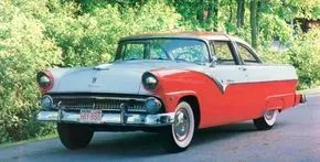 A vibrant red 1955 Ford Fairlane Crown Victoria parked on a bustling street.