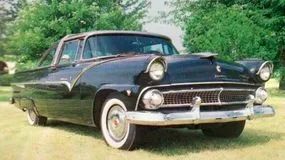 A sleek, all-black Ford Fairlane Crown Victoria equipped with classic whitewall tires.