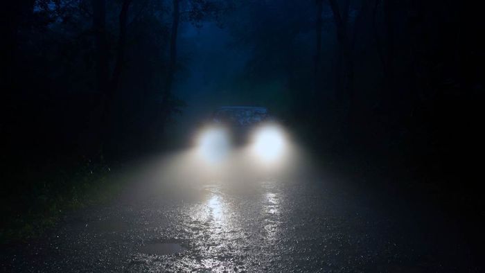 A car driving along a dark, secluded road at night