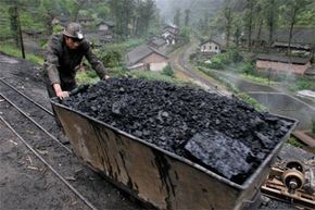 A miner pushes a cart filled with coal in Bagou village, located in China’s southwest Sichuan province, on April 13, 2006.