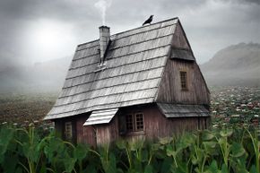 A crow perches atop an aged wooden house.