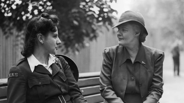 In 1941, Dorothy Thompson is seen conversing with an ambulance driver on a bench in London.