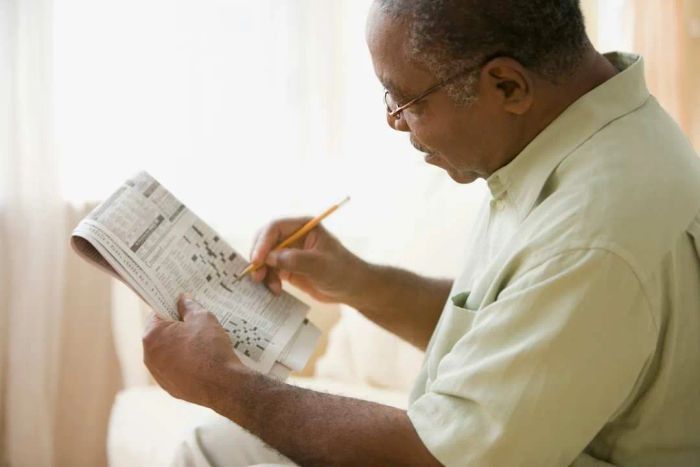 A Black man solving a crossword puzzle