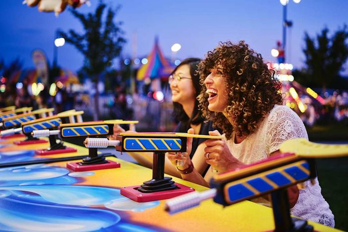 Two women enjoying a game at a summer carnival