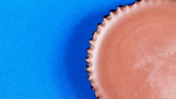 A close-up view of a peanut butter cup against a blue backdrop.