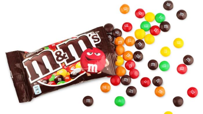 An open bag of plain M&Ms placed on a white surface.