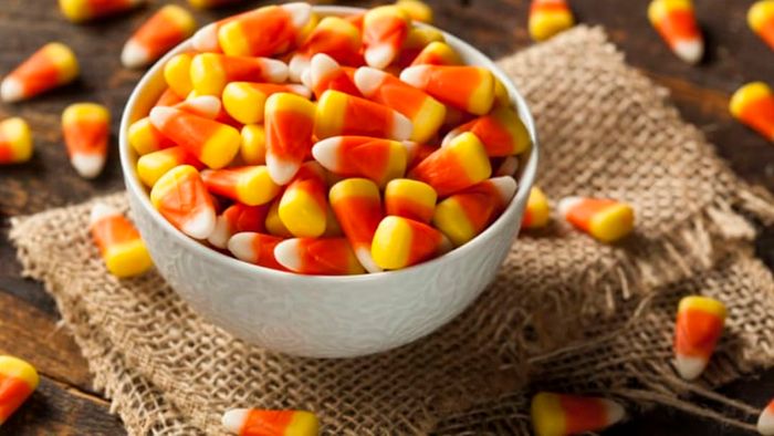 A burlap backdrop with a bowl filled with candy corn.
