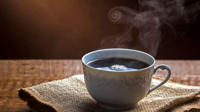A hot cup of coffee placed on a burlap cloth.