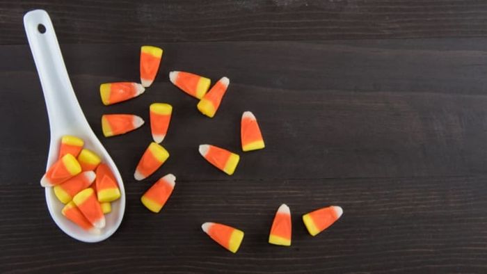 A white spoon filled with candy corn.