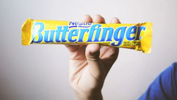 A person holding up a Butterfinger bar.