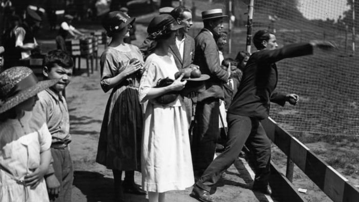 Participants attempt to topple coconuts in a 'coconut shy' game at a London fair in 1922.