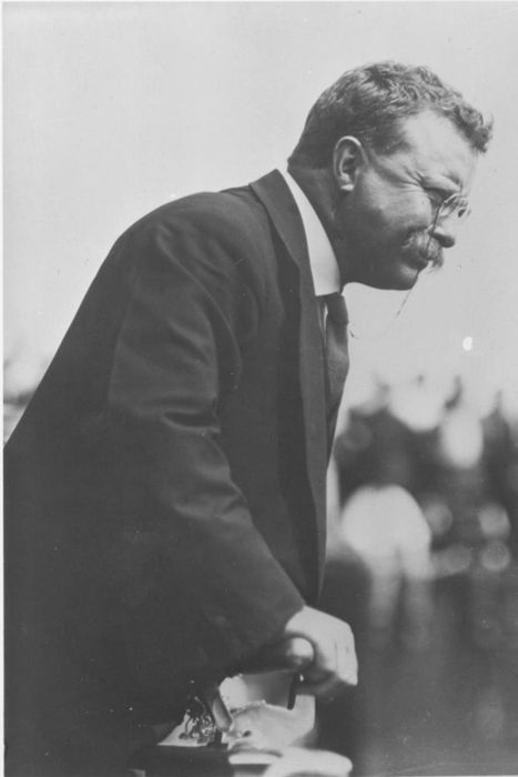Theodore Roosevelt leaning over a railing outdoors in 1910