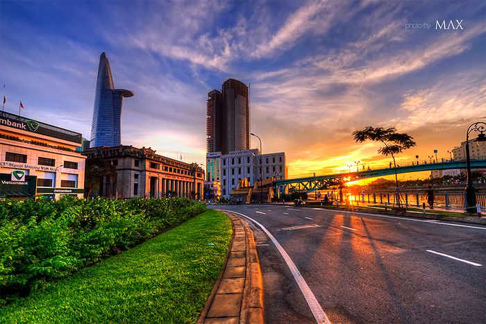 <p>Tiếng chim hót véo von trong vườn, âm thanh trong trẻo ấy đánh thức em dậy. Nhẹ nhàng bước ra khỏi giường, vươn vai xua tan cơn buồn ngủ còn sót lại. Đây là dịp hiếm hoi em được thức dậy sớm, tận hưởng một buổi sáng trong lành. Sau khi làm vệ sinh cá nhân, em quyết định tản bộ dọc con đường quen thuộc trong phố.</p><p><br></p><p>Trời còn sớm, không khí hơi se lạnh, sương vẫn còn bao phủ mọi thứ. Những tia nắng đầu tiên nhẹ nhàng xuyên qua từng kẽ lá, thả xuống những vệt sáng nhỏ xíu. Em hít thở không khí trong lành, mát mẻ của buổi sớm, từng cơn gió nhẹ lay động cây cối, những giọt sương trên lá như những viên ngọc nhỏ. Cảnh vật trở nên huyền bí, các ngôi nhà mờ ảo trong lớp sương sớm. Phía Đông, ông mặt trời đang dần thức giấc, vén màn sương mỏng để chiếu sáng đất trời. Trên bầu trời, những đám mây bồng bềnh trôi nhẹ nhàng.</p><p><br></p><p>Con đường trở nên vắng lặng, thỉnh thoảng chỉ có bóng dáng vài cô hàng rong đang chuẩn bị quầy bán, tiếng rao vang lên trong không khí tĩnh lặng. Ông mặt trời càng lúc càng nhô lên, không gian trở nên sáng rõ. Những tốp người đi bộ, các bà, các cô đi tập thể dục, trò chuyện rôm rả, tiếng cười nói khiến không khí càng thêm tươi vui. Những quán ăn sáng mở cửa, mùi thơm của bún, xôi, phở lan tỏa, khiến những người đi bộ chậm lại để thưởng thức.</p><p><br></p><p>Con đường phố rộng rãi, sạch sẽ, với những cây xanh vươn cành đón nắng. Mọi người bắt đầu một ngày mới đầy năng lượng, những dòng xe cộ nối đuôi nhau, tiếng còi xe rộn ràng. Trước cổng trường, các em học sinh trong bộ đồng phục trắng tinh khôi, khăn quàng đỏ tung bay trên vai, bước vào lớp học. Các bậc phụ huynh dặn dò con cái rồi cũng hòa vào dòng người. Mỗi sáng đều có những âm thanh, mùi hương, cảnh sắc đặc trưng, hòa quyện tạo nên bức tranh sống động của một ngày mới. Em luôn nhớ mãi hình ảnh êm đềm đó.</p>