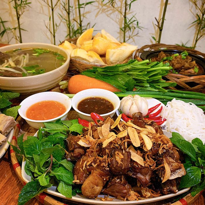 Hình ảnh: Góc quán ấm cúng với bộ bàn ghế gỗ mộc, đèn lồng đỏ và những món ăn truyền thống bày trên mâm gỗ